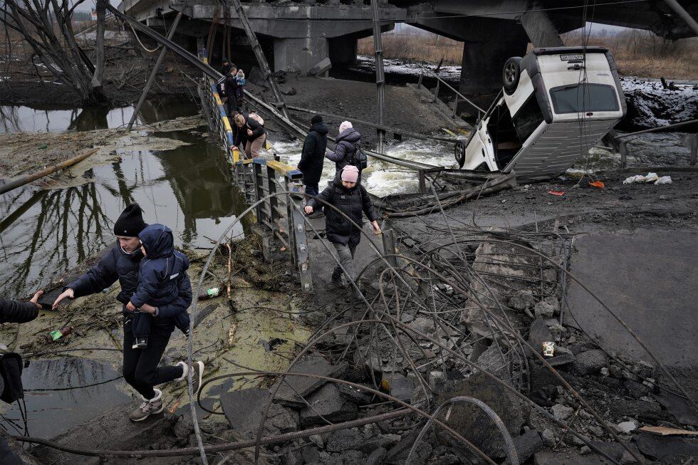 Varios civiles escapan de la guerra por los restos del puente sobre el río Irpin, a una veintena de kilómetros del centro de Kiev, que fue volado el 25 de febrero por el ejército ucranio para tratar de evitar la llegada de tropas rusas a la capital.