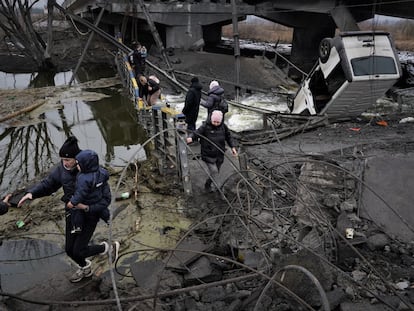Varios civiles intentan llegar a la estación de trenes de Kiev pisando los escombros del puente del río Irpin, que el ejército ucranio voló el viernes para evitar la entrada de tropas rusas la capital.