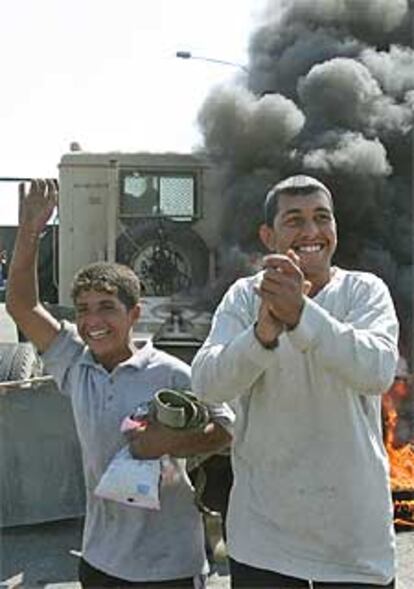 Jóvenes iraquíes celebran la quema de un camión militar estadounidense atacado hoy en la carretera del aeropuerto de Bagdad.