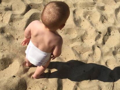 Un bebé juega en la playa.