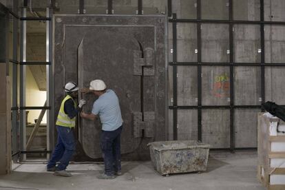 Dos trabajadores abren la antigua caja fuerte de Banesto, ahora en la galería comercial.