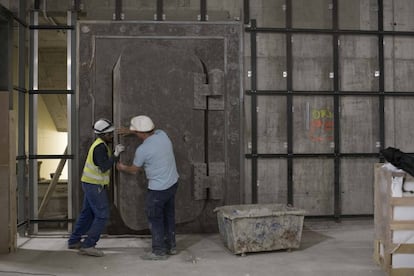 Dos trabajadores abren la antigua caja fuerte de Banesto, ahora en la galería comercial.