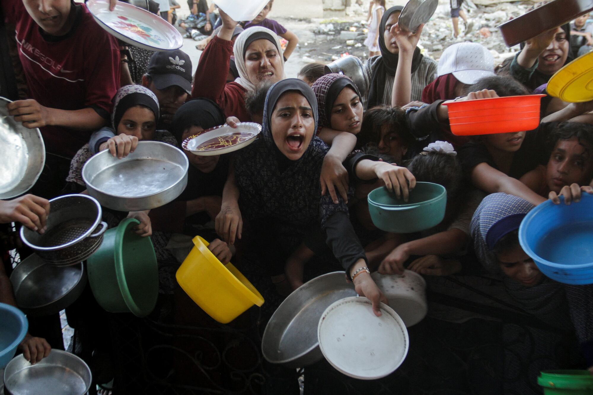 Palestinians react as they wait to receive food cooked by a charity kitchen, amid a hunger crisis as conflict between Israel and Hamas continues, in the northern Gaza Strip August 14, 2024. REUTERS/Mahmoud Issa