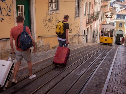 Dos turistas con sus maletas por la rua da Bica de Duarte Belo de Lisboa (Portugal).