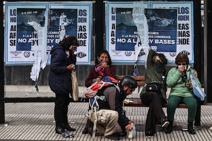 Mujeres y un periodista se protegen de los gases lacrimógenos en una estación de bus, mientras un voluntario les ayuda.