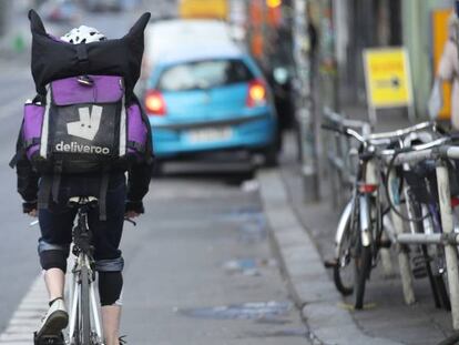 BERLIN, GERMANY - MARCH 09:  A man riding a bicycle for food delivery service Deliveroo passes through an intersection on March 9, 2018 in Berlin, Germany. A variety of food delivery setvices, including Lieferando, Deliveroo, Foodora and others, have established themselves across Germany. All depend heavily on part-time workers who receive little to no benifits. Some riders have sought to organize themselves into works councils, efforts that have so far failed or been thwarted by the companies.  (Photo by Sean Gallup/Getty Images)