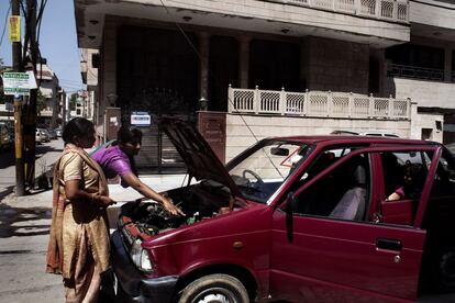 Dos aspirantes taxistas revisan el motor del coche antes de salir a una practica de conducción.