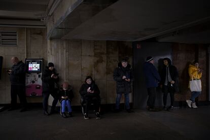 Un grupo de ciudadanos mira sus teléfonos móviles mientras se refugian en una estación de metro de Kiev durante una alarma antiaérea en diciembre de 2022.