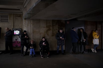 Ukrainians look at their cell phones while taking shelter in a Kyiv metro station during an air raid in December 2022.