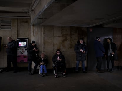 Un grupo de ciudadanos mira sus teléfonos móviles mientras se refugian en una estación de metro de Kiev durante una alarma antiaérea en diciembre de 2022.