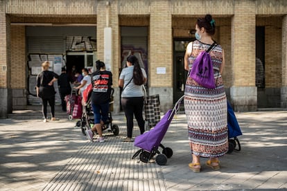 Un grupo de mujeres espera su turno en un local del Banco de Alimentos en el barrio de Orcasitas, Madrid.