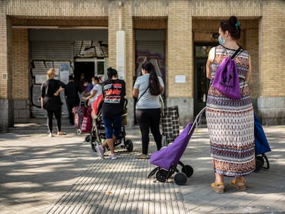 Un grupos de mujeres espera su turno en un local del Banco de Alimentos en el barrio de Orcasitas, Madrid.