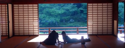 Dos personas miran el jardín desde el interior del templo Tenryu-ji, en Kioto