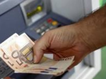 Un cliente de banca saca dinero de un cajero automático.