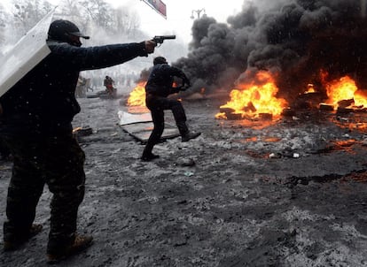 Un manifestante apunta con un arma a los policías antidisturbios durante los enfrentamientos que protagonizaron en el centro de Kiev. Dos activistas murieron a tiros durante los enfrentamientos.