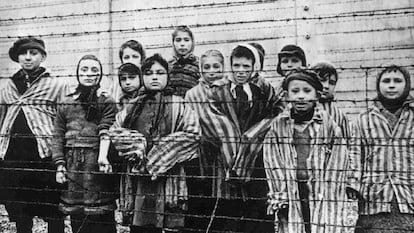 Um grupo de crianças atrás da cerca do campo nazista de Auschwitz.