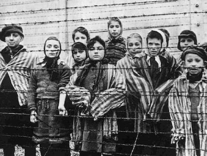 Um grupo de crianças atrás da cerca do campo nazista de Auschwitz.