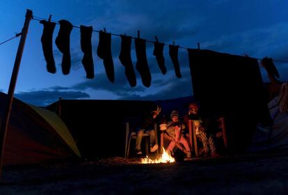 Unos niños se calientan alrededor de una fogata en un campamento improvisado para los migrantes y los refugiados cerca de la aldea de Idomeni.