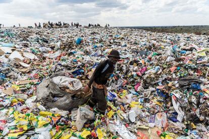 Un hombre arrastra un saco con papel para reciclar en un vertedero de Bulawayo (Zimbabue).