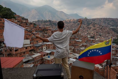 Un hombre ondea una bandera blanca desde el techo de una casa en el barrio José Félix Ribas de Petare, Caracas.