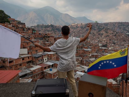 Un hombre ondea una bandera blanca desde el techo de una casa en el barrio José Félix Ribas de Petare, Caracas.