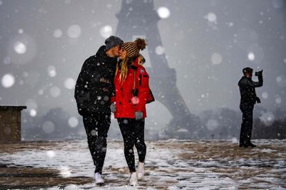 Una pareja se besa junto a la torre Eiffell de París.