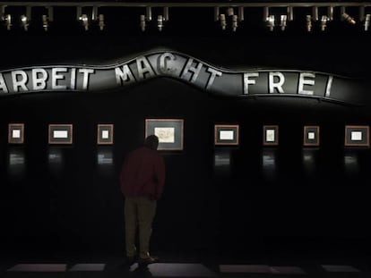 Uma sala da exposição, com o cartaz da entrada do campo de Auschwitz, onde se lê "O trabalho liberta".