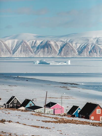 Una vista de Qaanaaq desde la que se ve la banquisa helada que cubre el fiordo con un iceberg en medio.