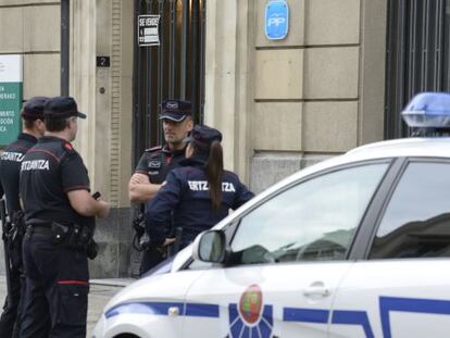 Agentes de la Ertzaintza custodian la sede del PP en Vitoria mientras comprueban un paquete sospechoso encontrado en la entrada.