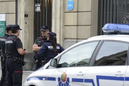 Agentes de la Ertzaintza custodian la sede del PP en Vitoria mientras comprueban un paquete sospechoso encontrado en la entrada.