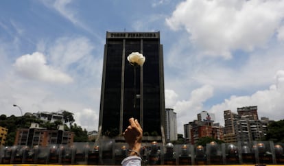 Una manifestante levanta una flor frente a la policía antidisturbios durante la marcha de mujeres contra Nicolás Maduro, el 6 de mayo de 2017 en Caracas. 
