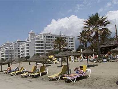 Residentes en Banana Beach toman el sol junto a la urbanización de Marbella.