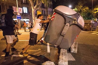 Two protesters push over a garbage container.