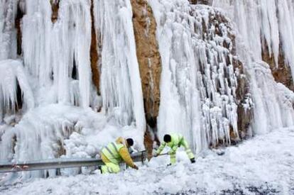 Operarios del servicio de conservación de carreteras intentan quitar los trozos de hielo en la NA-137 (Navarra)
