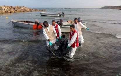 Trabajadores de una ONG llevan una bolsa con el cadáver de un emigrante en una playa de la ciudad costera de Tajoura, al este de Trípoli, en Libia.