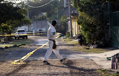 Un médico forense cerca con cinta policial el lugar donde fue asesinada una persona, en una imagen de archivo.