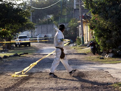 Un médico forense cerca con cinta policial el lugar donde fue asesinada una persona, en una imagen de archivo.