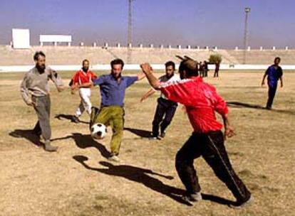 Varios afganos juegan al fútbol en el estadio de Kabul, que fue usado por los talibanes para las ejecuciones.
