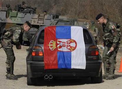 Soldados de la OTAN detienen un coche con una bandera serbia cerca de Mitrovica, en la carretera que une esta ciudad con Belgrado.
