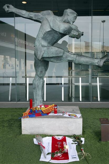 Ofrendas para rendir homenaje al futbolista ante la escultura del legendario jugador y entrenador holandés Johan Cruyff, en la entrada de tribuna del Camp Nou.