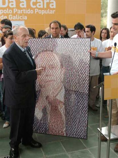 Fraga recibe una imagen con su foto electoral, realizada con pequeñas fotografías de militantes de Nuevas Generaciones, durante el acto que celebró el Partido Popular de Galicia en un hotel de Santiago de cara a las elecciones del 19 de junio.