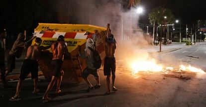 Un grupo de hombres empuja un contenedor para hacer una barricada en la ciudad brasileña de Vitória.