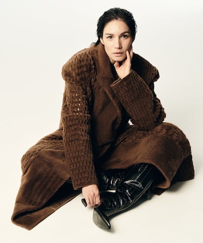 Mariela Garriga lleva abrigo largo de borrego perforado con cinturón y botas Fendi Arco de anguila, todo de FENDI.