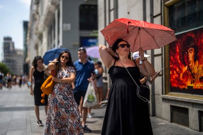 Varias personas caminaban con paraguas el lunes por el centro de Madrid para protegerse del sol.