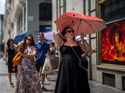 Varias personas caminaban con paraguas el lunes por el centro de Madrid para protegerse del sol.