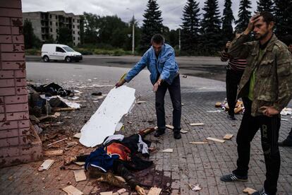 Un hombre observa el cuerpo de una mujer fallecida por el bombardero en laciudad de Makiyivka.