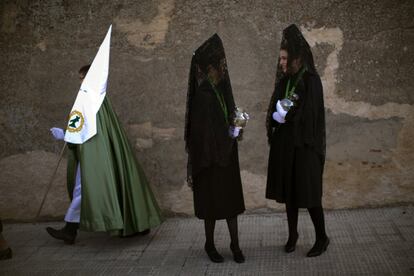 Un penitente camina junto a dos mujeres ataviadas con la tradicional mantilla antes de participar en la procesión de la Virgen de la Esperanza, en Zamora.