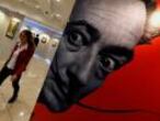 FILE PHOTO: A visitor walks past a portrait of Salvador Dali during the exhibition "Cryptography" in St. Petersburg