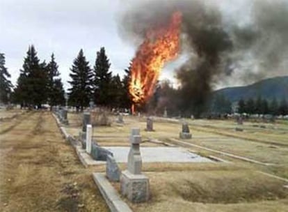 Vista del cementerio contra el que se estrelló el avión, con el aparato en llamas al fondo.