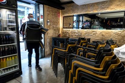 El propietario de un bar de Valencia recoge las sillas de la terraza en plena pandemia de covid-19.